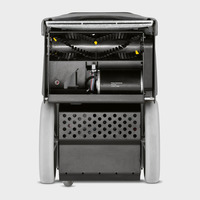 Kärcher sweeper interior showing rotating brush, motor, and perforated panel, with grey wheels on either side.
