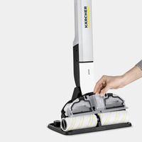 Hand adjusting the roller on a Kärcher floor cleaner, featuring dual white rollers with yellow stripes, against a plain background.