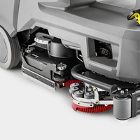 Close-up of a Kärcher floor scrubber's underside, showing red brushes, wheels, and grey casing components.
