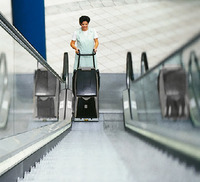 Person operating a Kärcher escalator cleaner on a moving escalator in a tiled indoor setting.