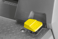 Yellow foot pedal on grey textured surface with embossed symbols indicating operation instructions.