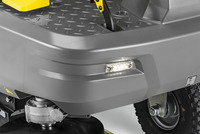 Close-up of a Kärcher ride-on scrubber with a grey body, LED light, yellow pedal, and visible wheel and brush mechanism.