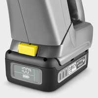 Close-up of a Kärcher 18V battery with a digital display showing 100% charge, featuring a yellow release button.