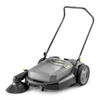 Kärcher push sweeper with a large handle, grey body, and rotating brush, designed for outdoor cleaning tasks.