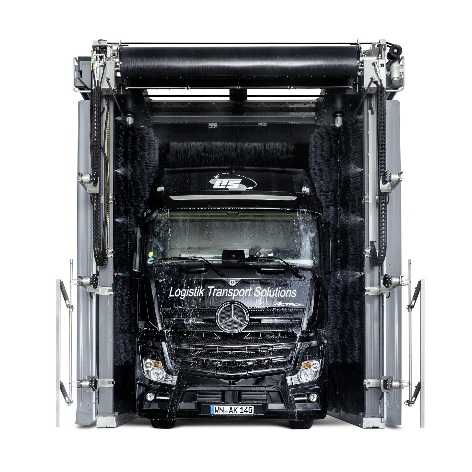 Schwarzer Mercedes-LKW in einer automatischen Waschanlage, umgeben von rotierenden Bürsten.