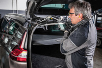 Person using a Kärcher high-pressure cleaner on the interior of a car boot in a garage setting.