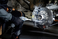 Person cleaning a car brake disc with a Kärcher high-pressure cleaner in a garage setting.