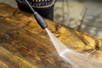 Kärcher high-pressure cleaner spraying water on a wooden surface outdoors.