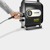 Hand connecting a hose to a Kärcher Silent Technology high-pressure cleaner, featuring a sleek black design and handle.