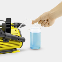 Hand inserting tube into beaker of blue liquid next to Kärcher high-pressure cleaner.