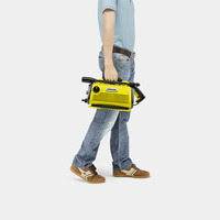 Man in jeans and blue shirt carrying a yellow Kärcher high-pressure cleaner.