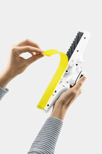 Hands attaching a yellow blade to a white Kärcher window vac against a plain background.