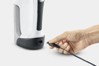 Hand plugging a cable into the charging port of a Kärcher window vac.