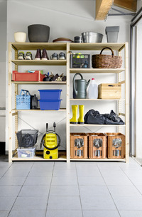 Garage shelves with various items, including a Kärcher high-pressure cleaner, gardening tools, yellow boots, and storage bins.