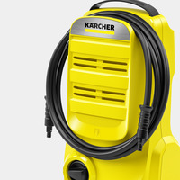 Yellow Kärcher high-pressure cleaner with coiled black hose and control dial, featuring the Kärcher logo on a metallic panel.