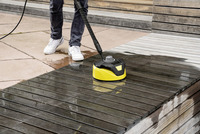 Person cleaning wooden deck with Kärcher surface cleaner outdoors.