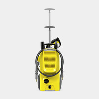 Yellow Kärcher high-pressure cleaner with hose and spray gun attachment, standing upright on a light grey background.