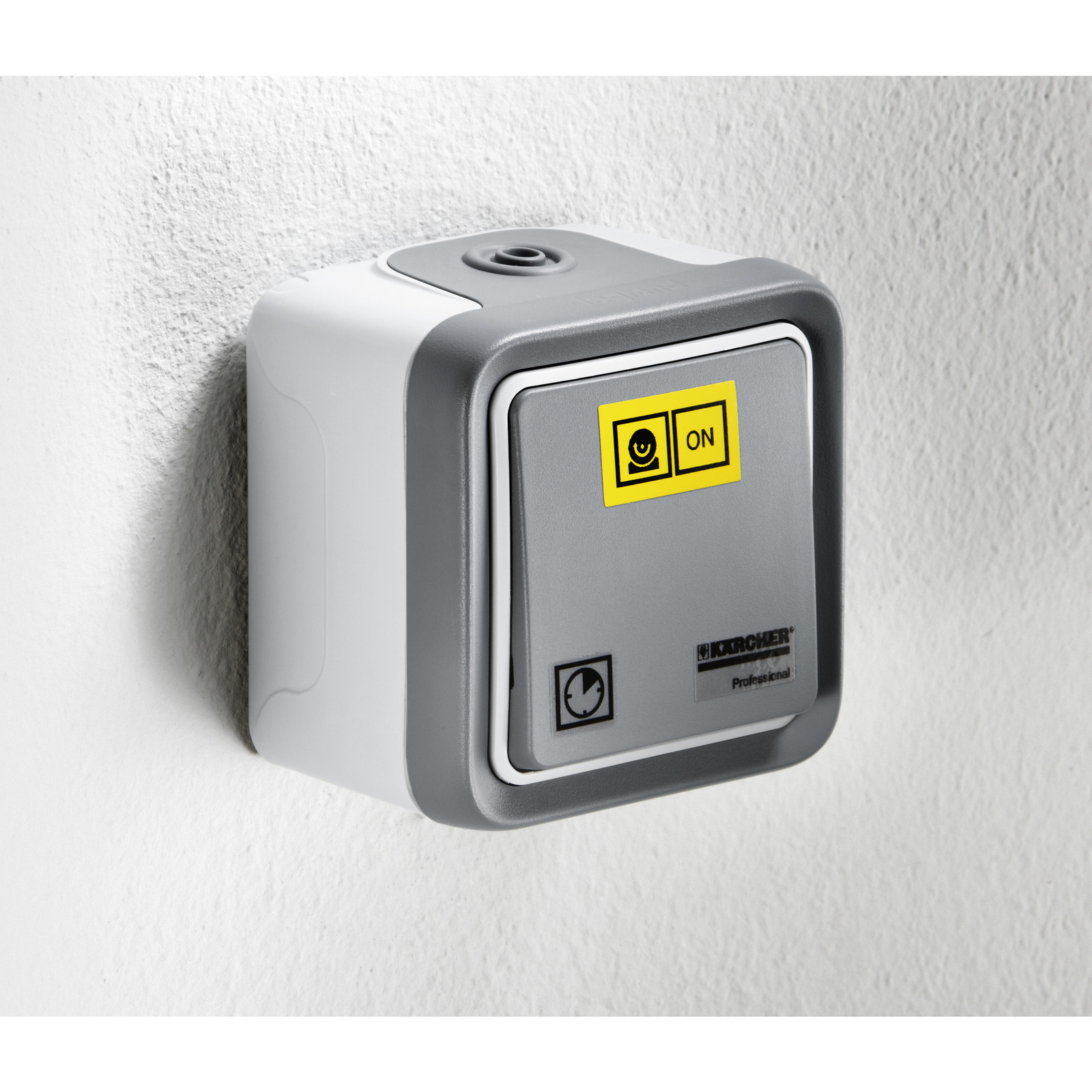 Kärcher wall-mounted switch with grey casing and yellow labels, installed on a white textured wall.