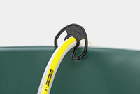 Kärcher hose holder securing a yellow and white hose on a green container edge.