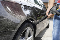 Person cleaning a black car's wheel arch with a Kärcher high-pressure cleaner outdoors.