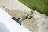 Person using a Kärcher high-pressure cleaner on a paved outdoor area, viewed from above.