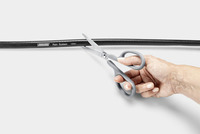 Hand holding scissors cutting a Kärcher Rain System hose against a plain white background.