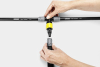 Hands connecting Kärcher Rain System hoses with a yellow connector against a white background.