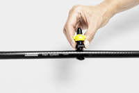Hand adjusting a yellow nozzle on a Kärcher Rain System hose against a plain background.