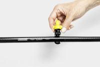Hand adjusting a yellow nozzle on a Kärcher Rain System hose against a plain background.