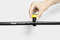 Hand adjusting a yellow nozzle on a Kärcher Rain System hose against a plain background.