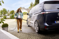 Person using a Kärcher high-pressure cleaner to wash a dark blue van in a residential driveway.