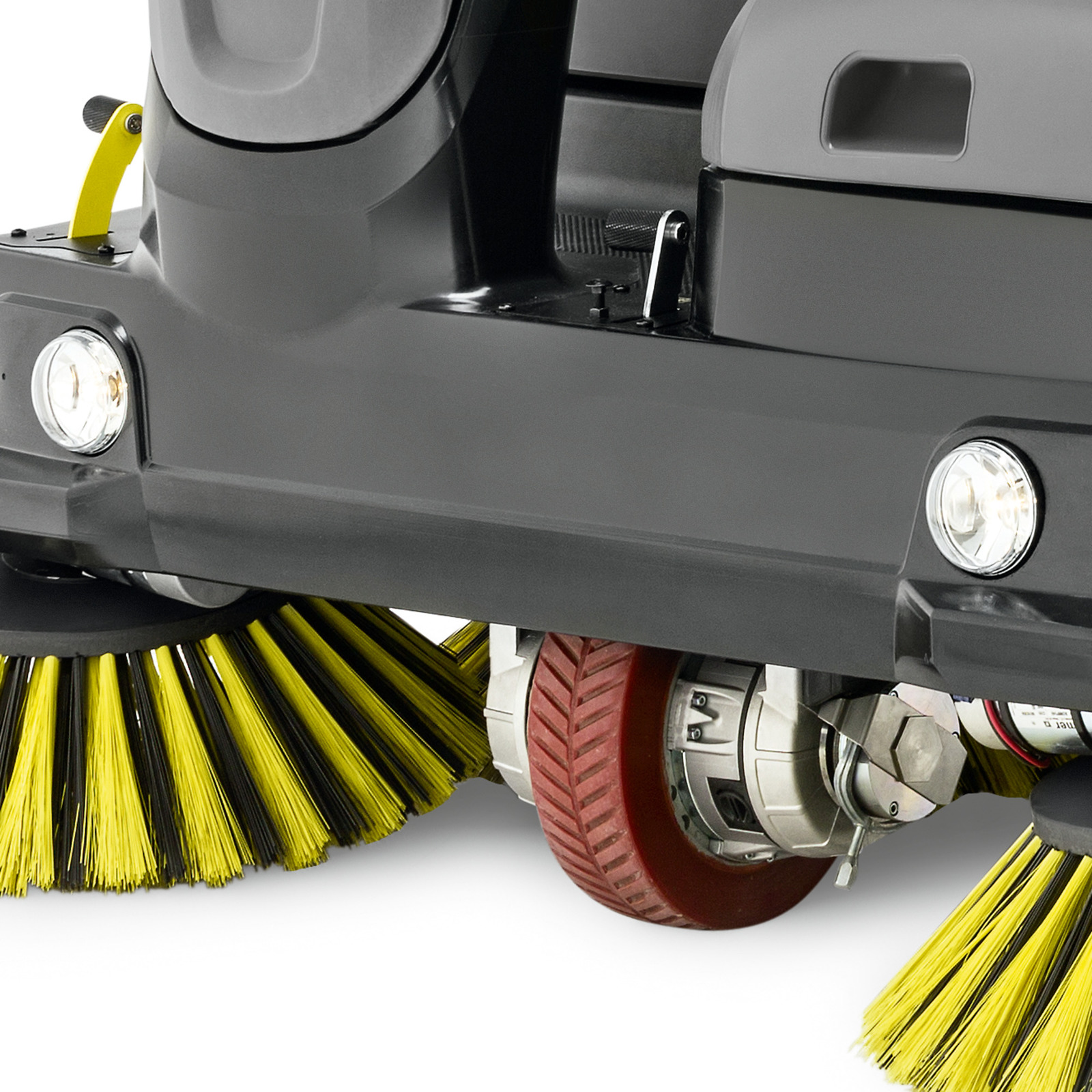 Close-up of a Kärcher floor sweeper with yellow brushes and red wheels, featuring two front headlights. Close-up of a Kärcher floor sweeper with yellow brushes and red wheels, featuring two front headlights.