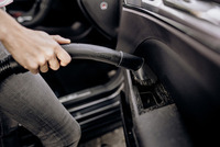Hand using Kärcher vacuum cleaner to clean car interior door panel.
