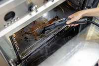 Hand cleaning oven interior with Kärcher steam cleaner, removing grime from the bottom surface.