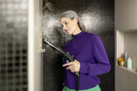 Person using a Kärcher steam cleaner on a tiled wall in a modern bathroom setting.