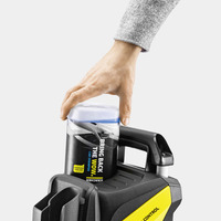 Hand placing Kärcher car shampoo bottle on Kärcher pressure washer, with a grey sleeve visible.