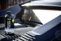Kärcher polish and wax bottle on a shiny car surface, reflecting sunlight.
