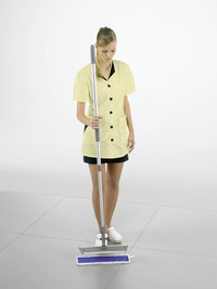 Person in yellow uniform holding a mop on a tiled floor in a bright indoor setting.