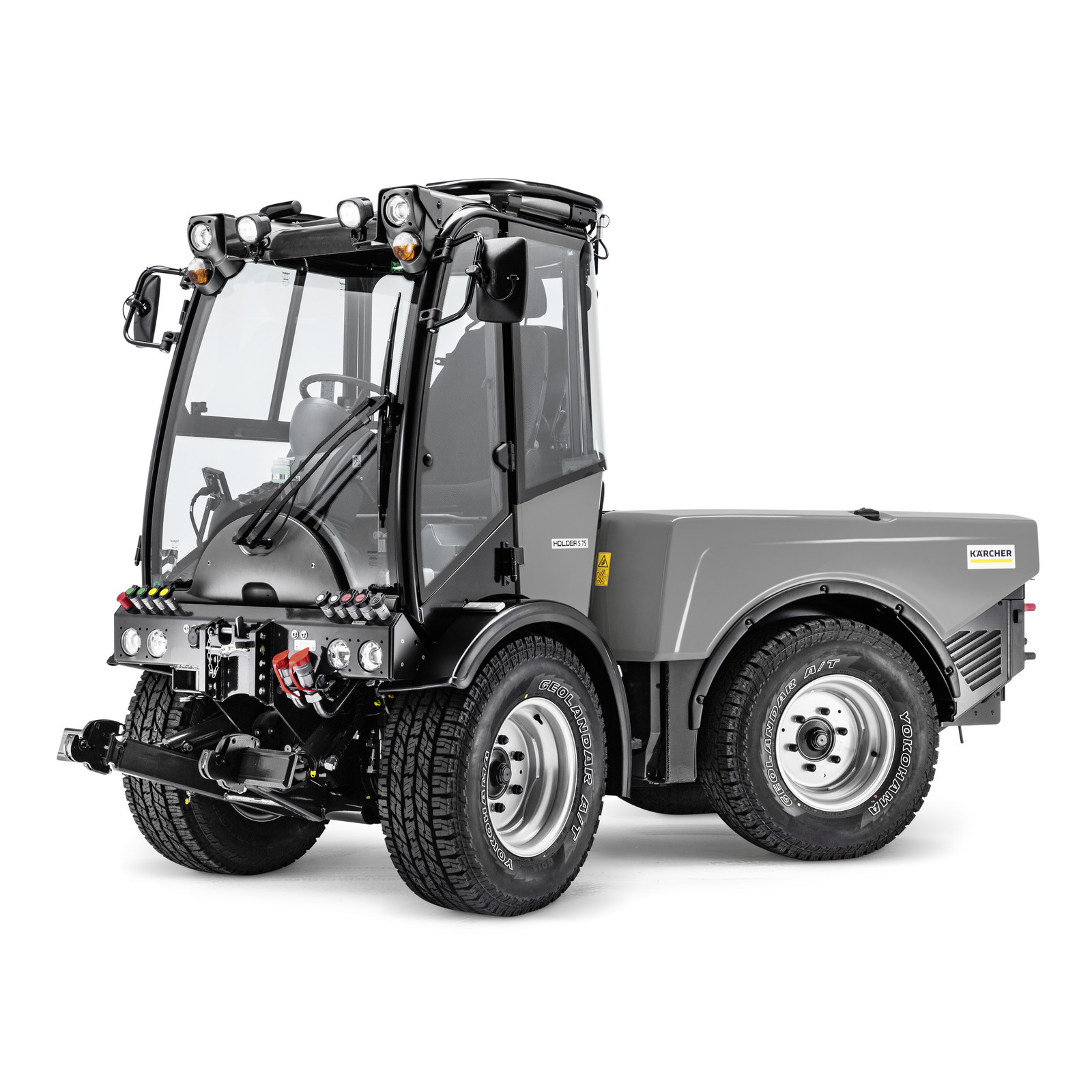 Grey Kärcher utility vehicle with enclosed cab, large tyres, and visible headlights, shown in a studio setting.