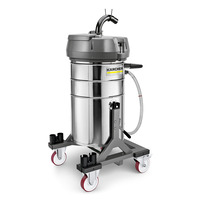 Kärcher industrial vacuum cleaner with stainless steel body, mounted on a wheeled base with red and white wheels.